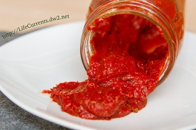red sauce pouring out of a jar onto a white plate.