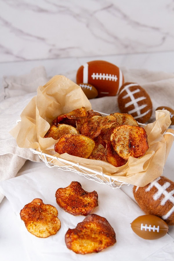 BBQ potato chips in a wire basket with some football decorations around.