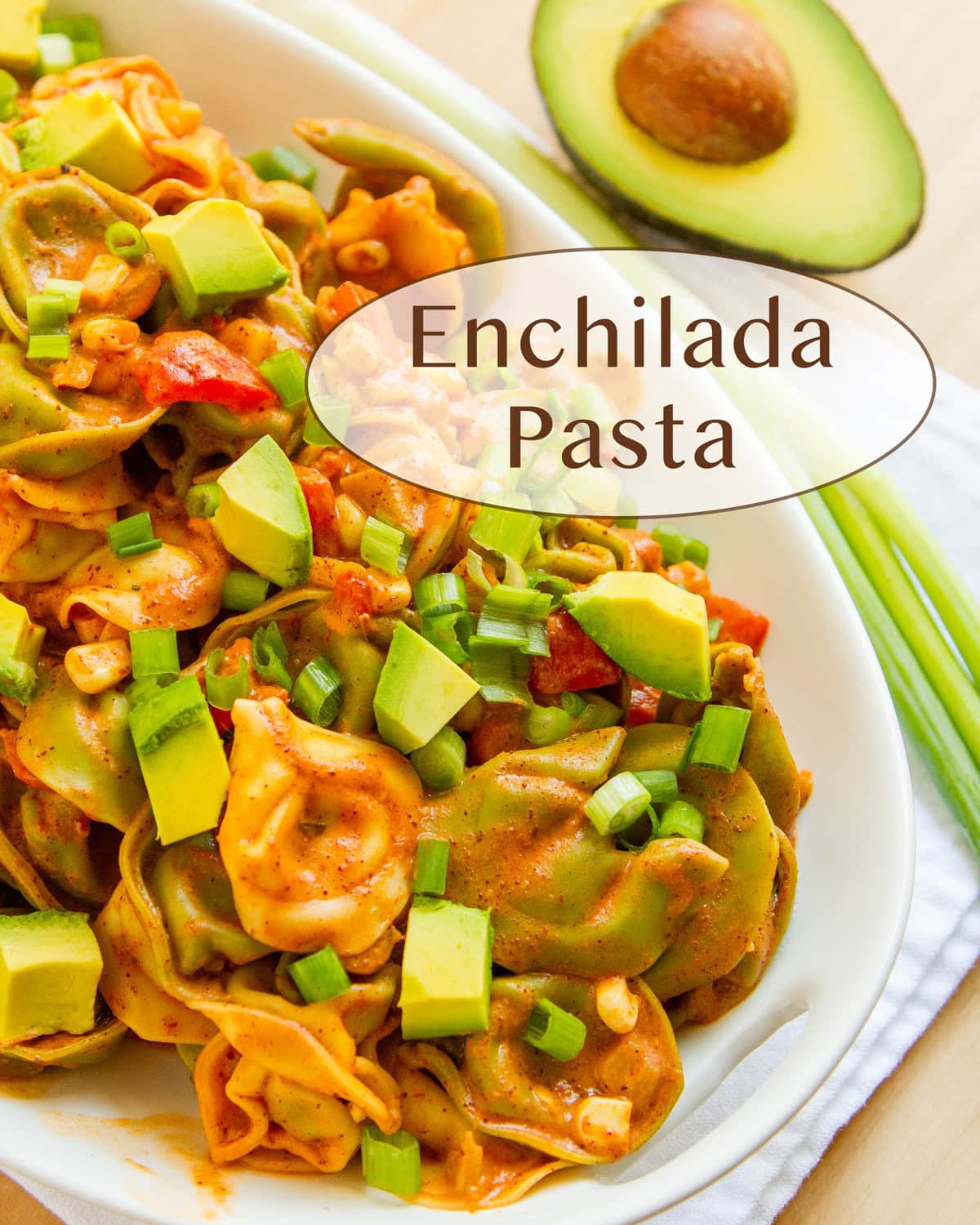 a platter of tortellini with Mexican sauce and veggies and an avocado in the upper right.