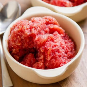 a bowl filled with Cherry Lambic Granita a frozen dessert and a spoon next to it.