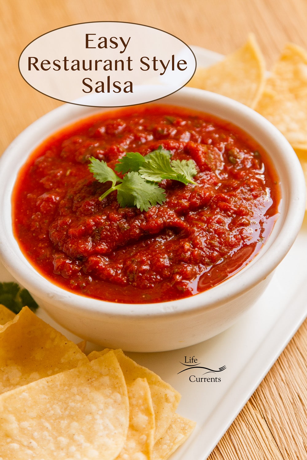 a white bowl filled with salsa topped with a cilantro leaf and chips next to it.