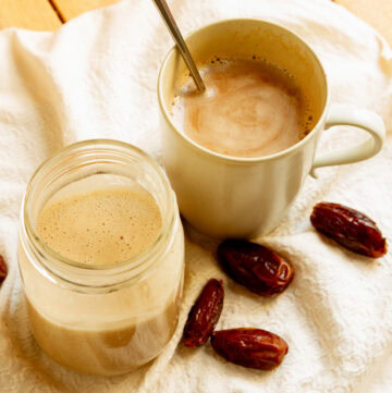 a Mason jar with coconut milk coffee creamer next to a mug of coffee with the creamer in it.