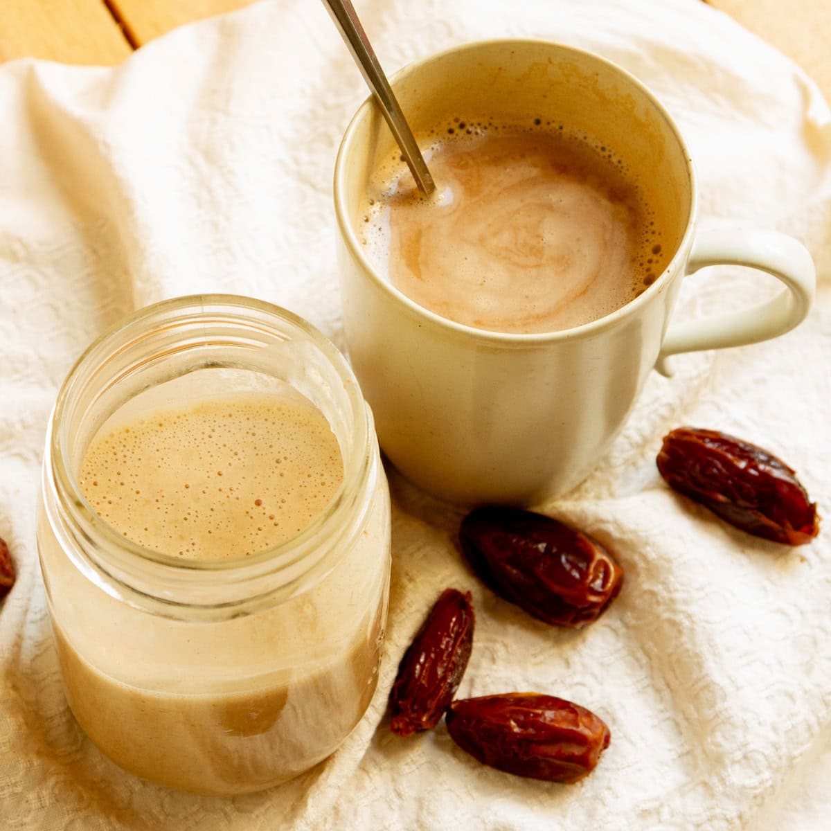a Mason jar with coconut milk coffee creamer next to a mug of coffee with the creamer in it.