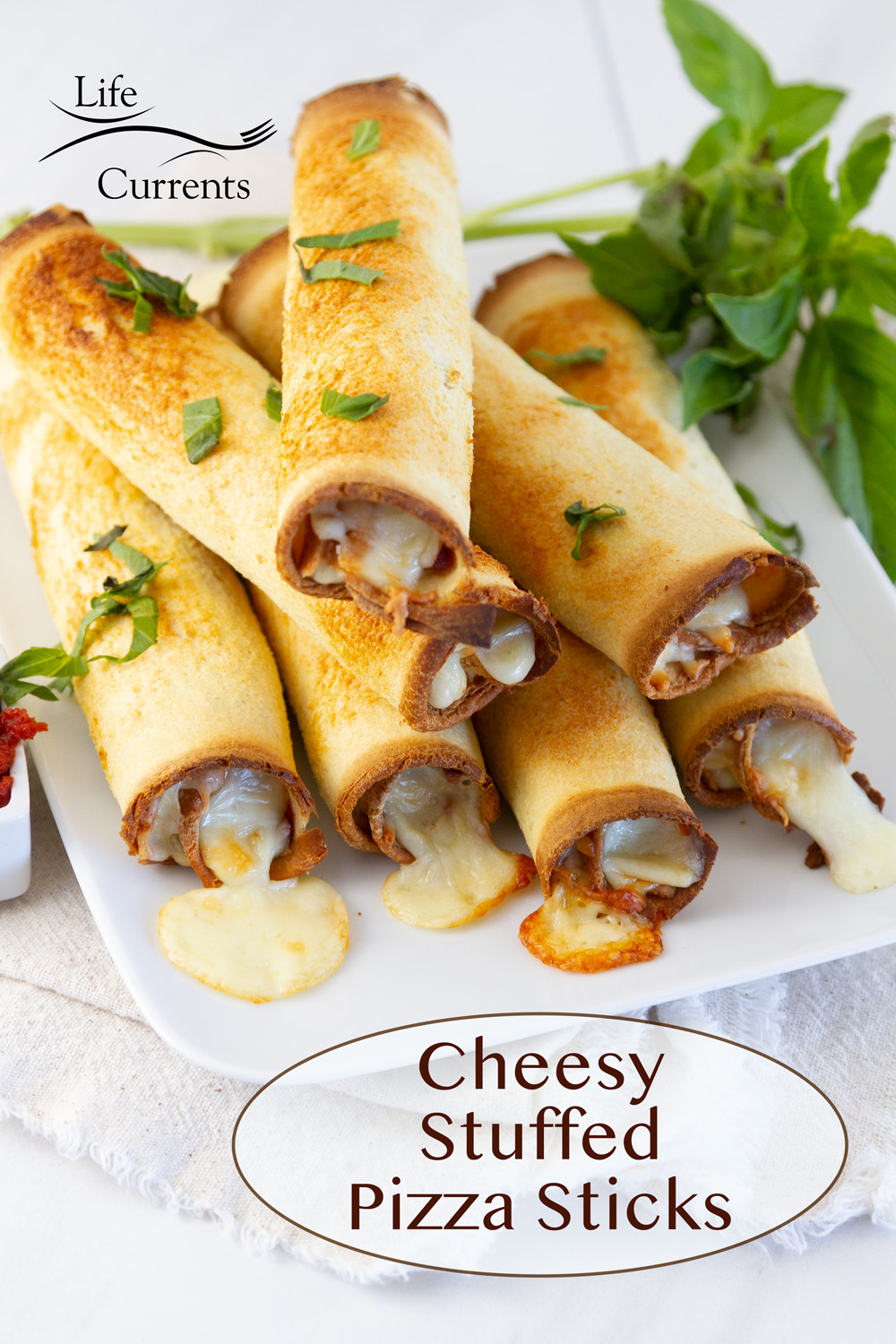 Cheesy Stuffed Pizza Sticks stacked on a plate with fresh basil in the background.