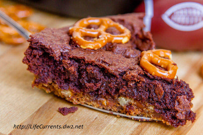 A close up on a slice of brownie topped with pretzels.