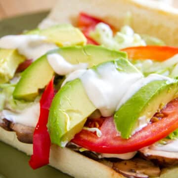an open sandwich with avocado, tomato, red pepper, lettuce and Alfredo sauce.