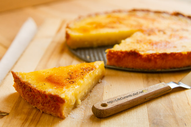 Meyer Lemon Br&ucirc;l&eacute;e Tart on a wooden background with a pie server. 