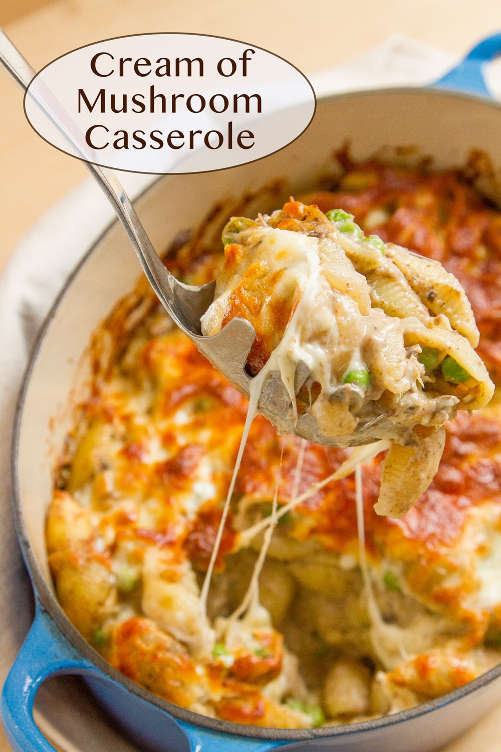 Cream of mushroom casserole in a blue casserole dish being served up by a spoon.