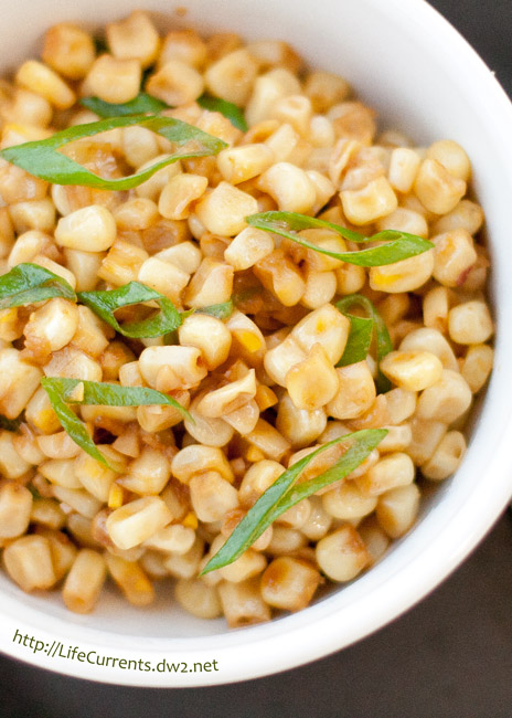 corn garnished with green onions in a white bowl.