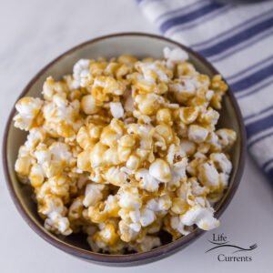 a bowl of caramel corn with a blue striped towel in the background
