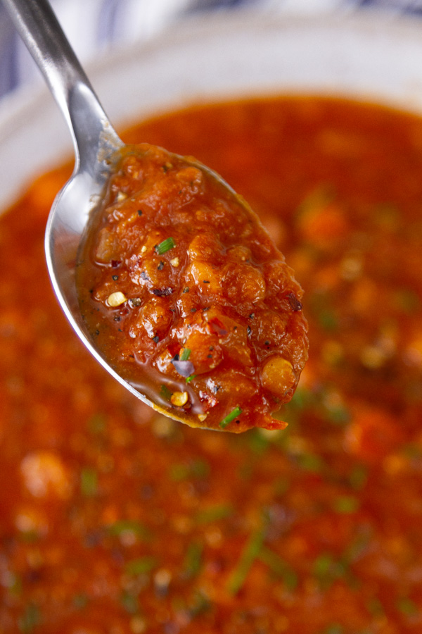 a spoonfull of soup in front of the bowl of soup.