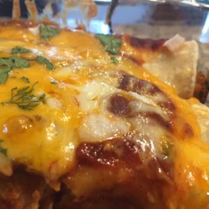 crab and shrimp enchiladas in a baking pan covered with cheese.