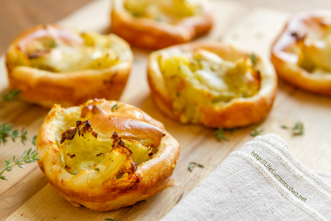 potato puffs on a wooden cutting board with fresh thyme and a cloth napkin.