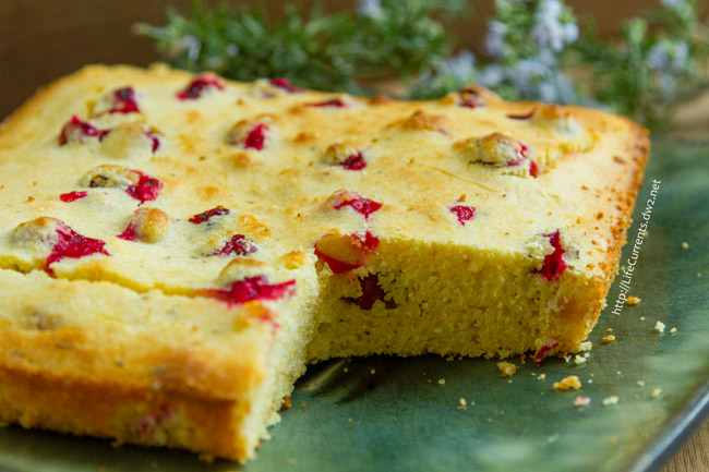 Cornbread studded with cranberries on a green plate.
