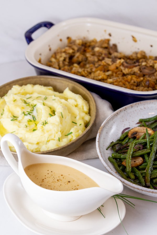 Thanksgiving dinner dishes with stuffing, green beans, gravy, and mashed potatoes.