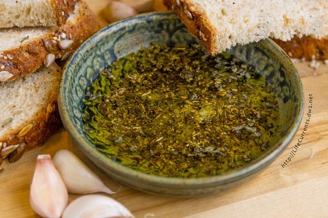 bread dipping oil in a bowl with slices of bread and cloves of garlic