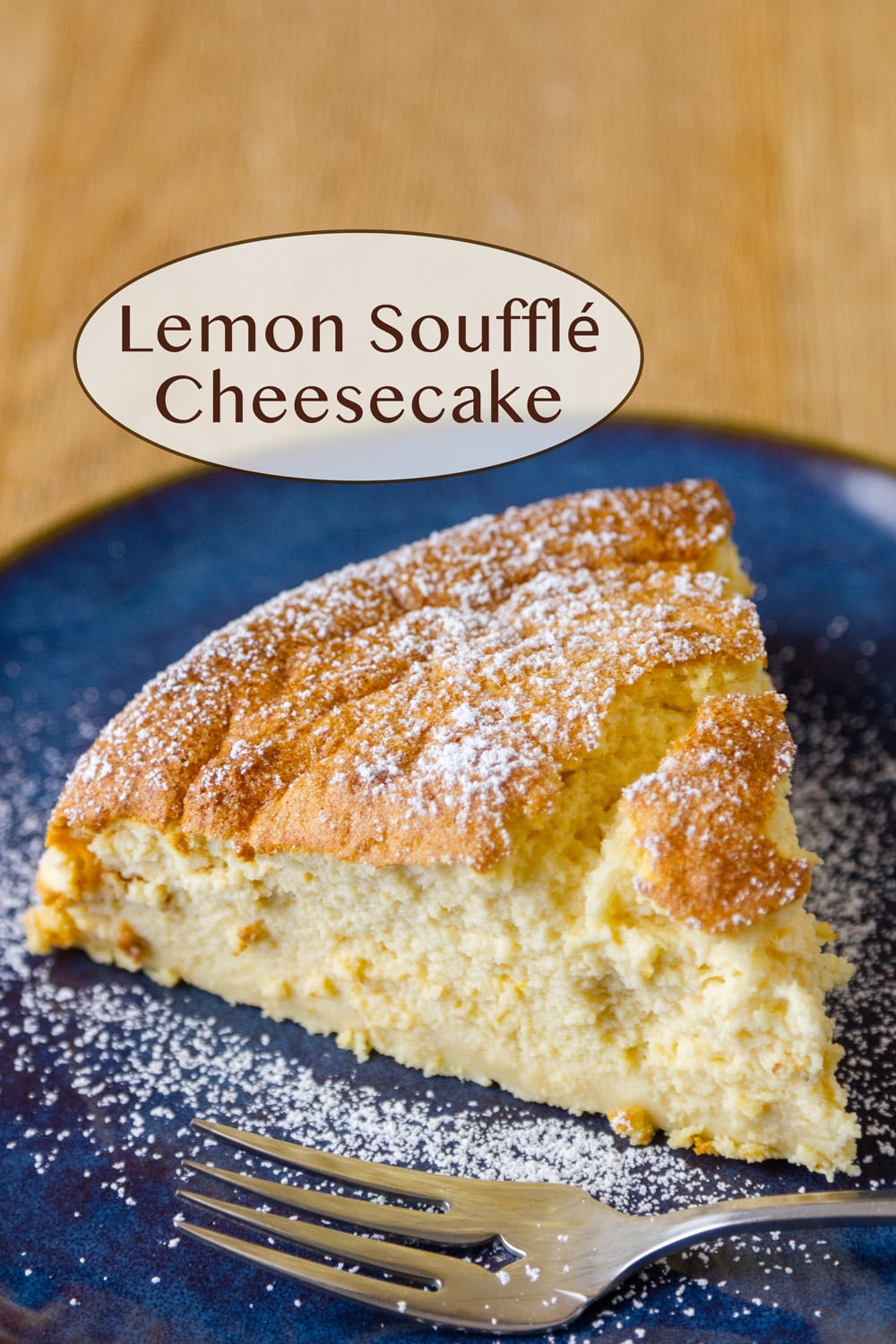 A slice of cheesecake on a blue plate with a fork in the lower area all dusted with powdered sugar.
