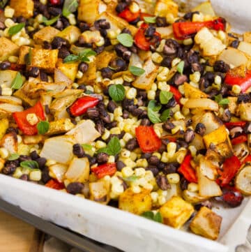 square crop of roasted vegetables in a white casserole dish.