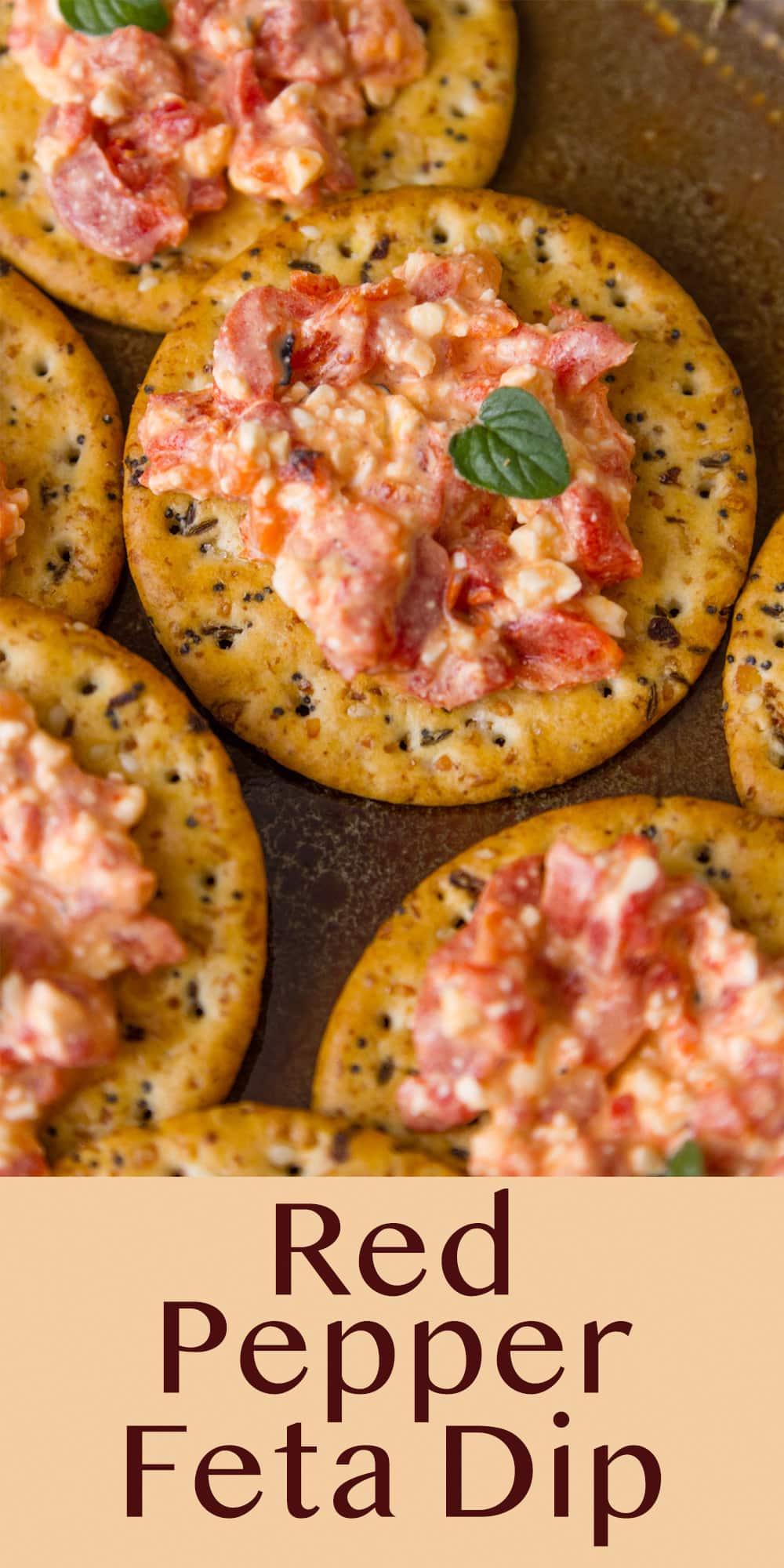 crackers topped with red pepper feta dip that's been left chunky and some fresh oregano garnish.