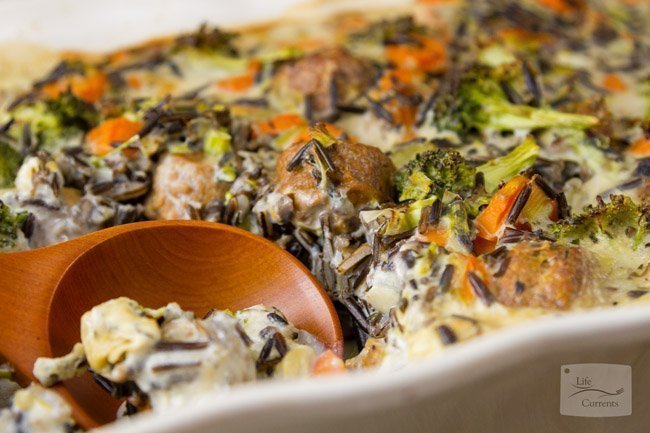 casserole being scooped up by a wooden spoon.