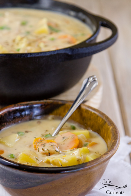 a bowl of vegetable soup in front of a large pot of soup.