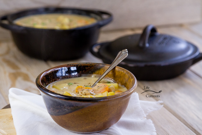 a bowl of soup with a spoon in it in front of a pot of soup.