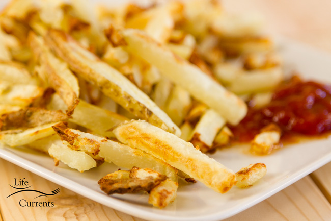 a plate full of French fries with ketchup.