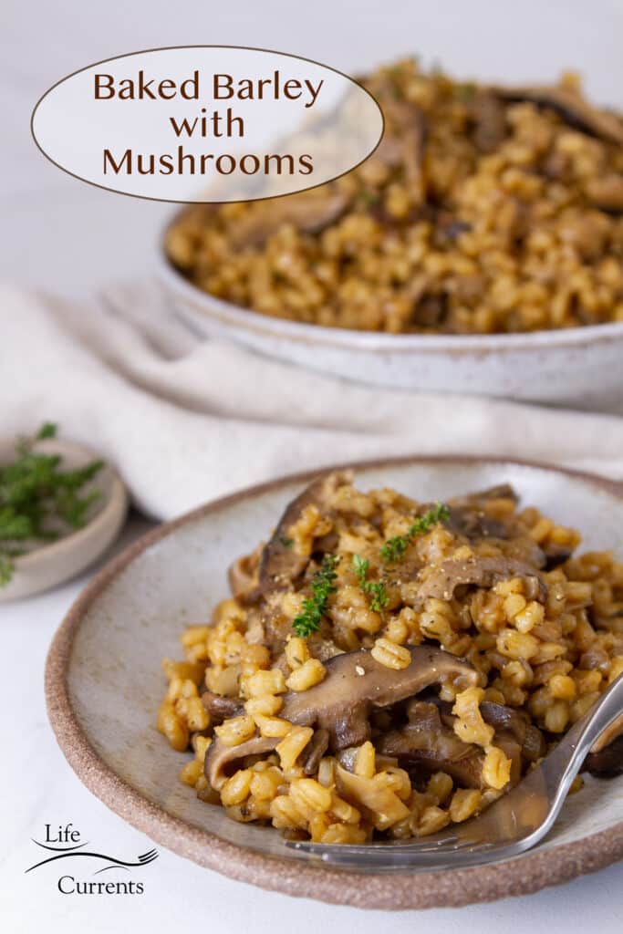 a plate with barley and mushrooms and a fork in front of the serving dish of barley, title on upper left Baked Barley with Mushrooms.