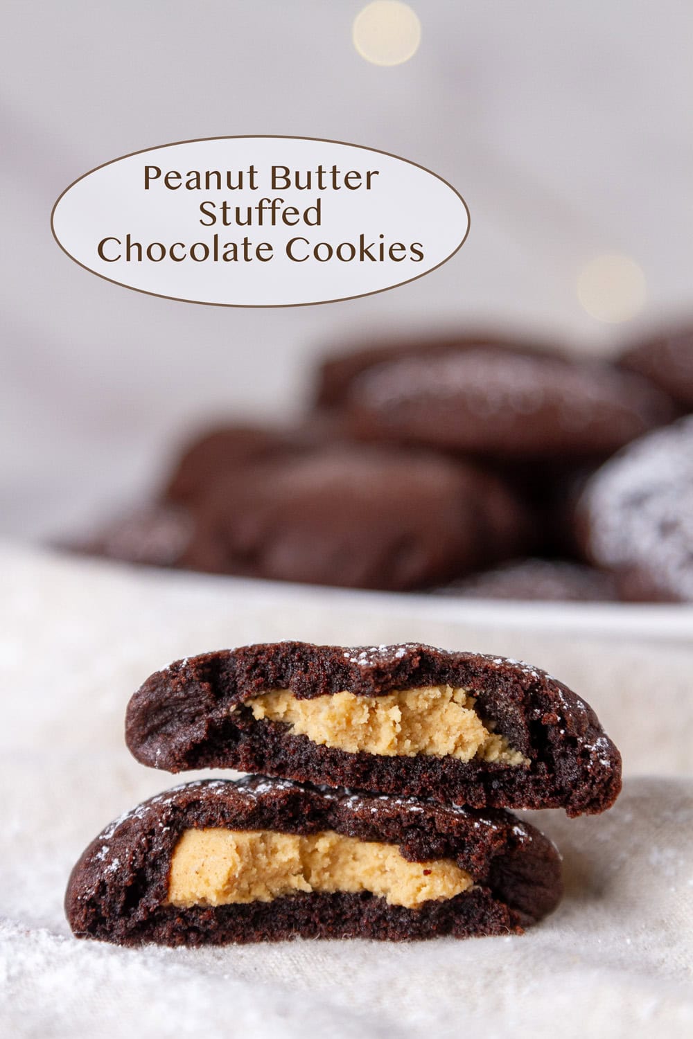 a chocolate cookie filled with peanut butter broken in half so you can see the inside in front of a plate of cookies.