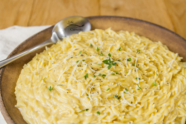 A bowl of pasta in a creamy sauce with a serving spoon.