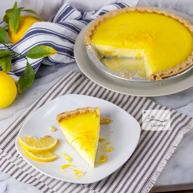 Grandma&rsquo;s Lemon Custard Pie a slice of pie garnished with lemon slices served next to the whole pie and some whole lemons