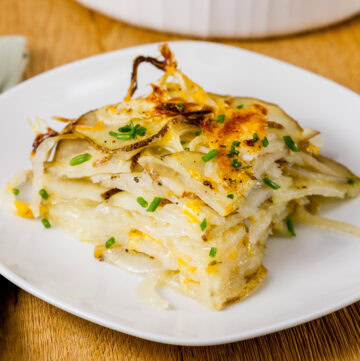 a serving of layered potato and onion baked side dish on a white plate.
