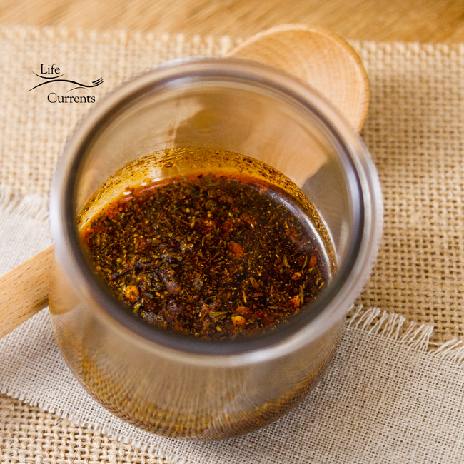 Cajun Spice Oil in a glass jar with a wooden spoon