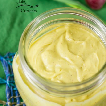 The Best Avocado Sauce! in a jar with a green cloth in the background