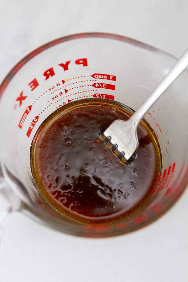 Asian sauce in a glass measuing cup with a fork in it to stir it.
