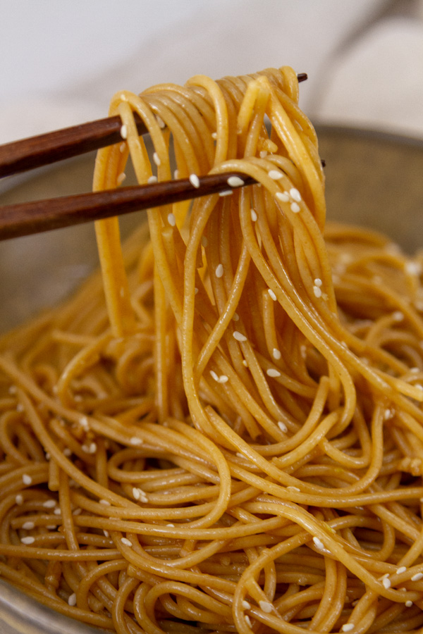 noodles being picked up by chopsticks.