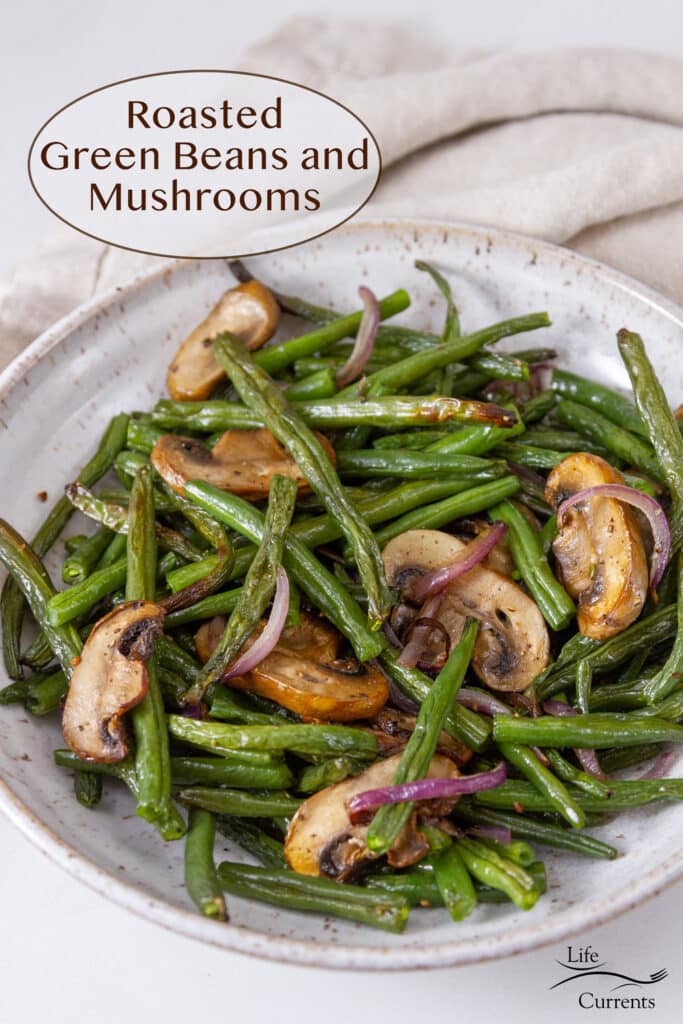 A white bowl filled with Roasted Green Beans and Mushrooms and red onions, title on upper left.
