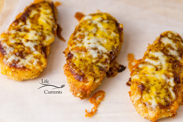 three chicken fingers with sauce and cheese