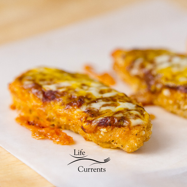 close up on baked chicken fingers with sauce and cheese