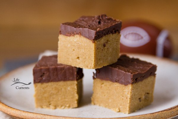 peanut butter and chocolate bars stacked on a plate with a football in the background.