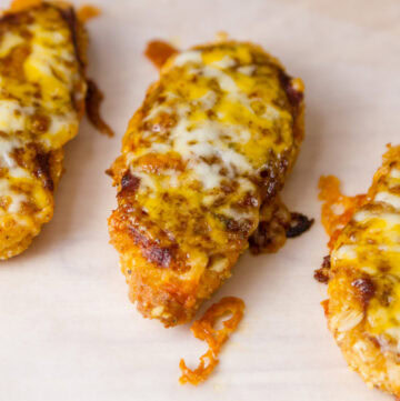 three chicken tenders topped with red sauce and cheese.