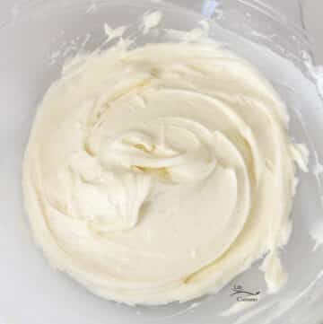 square crop of white frosting in a glass bowl.