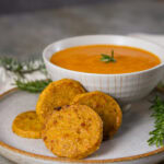 square crop of crackers on a plate in front of a bowl of soup.