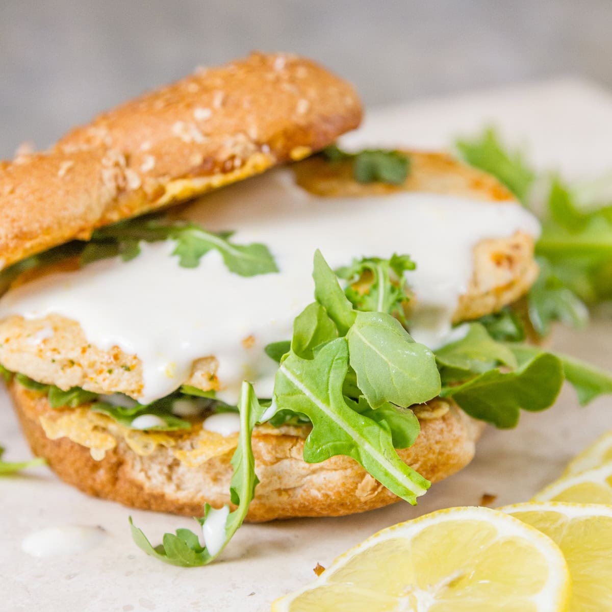 a sandwich with chicken, arugula, and some sliced lemons by it.