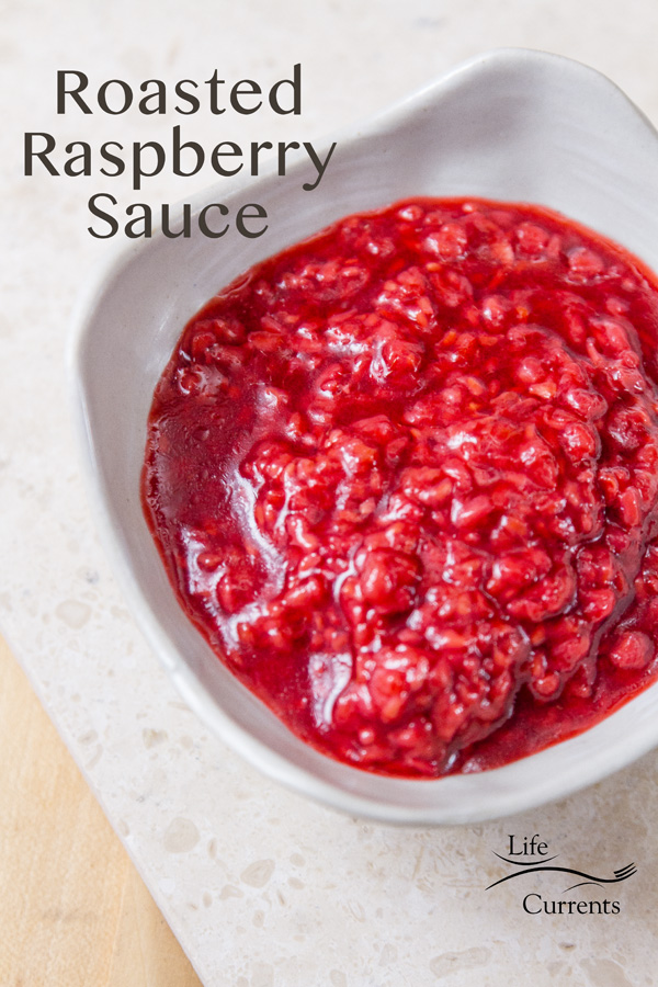 Tart bright red roasted raspberry sauce in a white dish on a white background