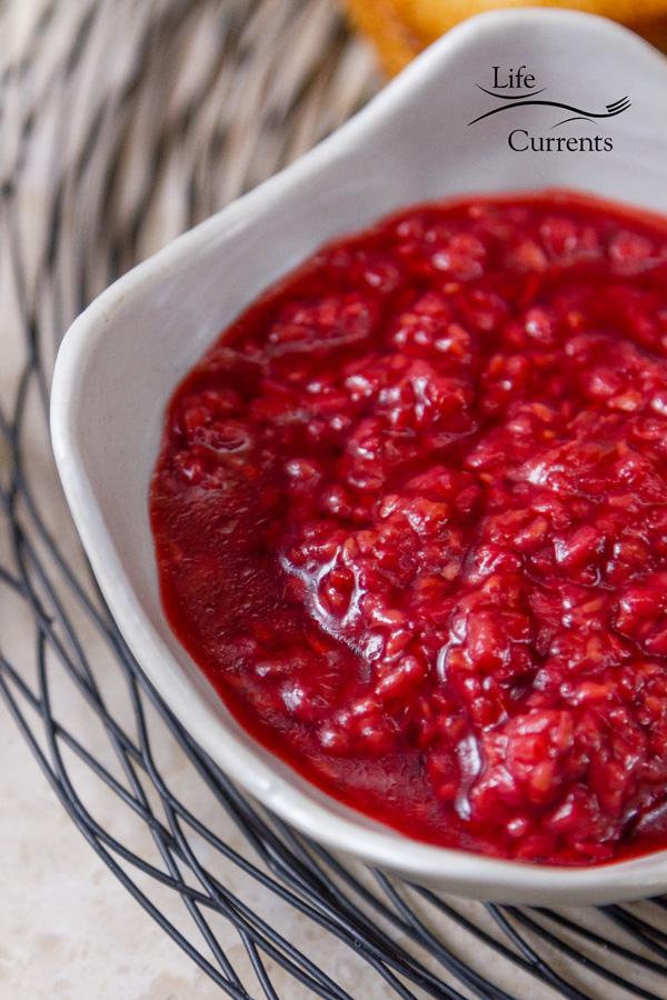 red homemade roasted raspberry sauce in a white dish on a wire rack