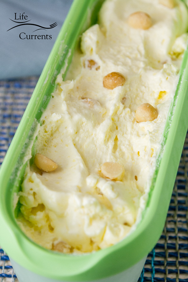 Pineapple Macadamia Nut Ice Cream in a green ice cream container on blue fabric 