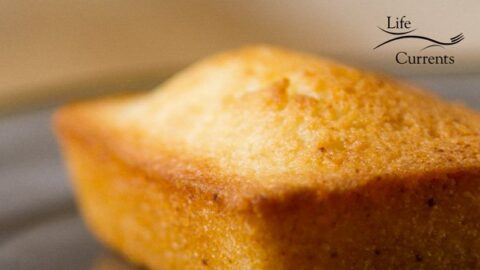 square image of the financier cake, a simple almond cake on a gray plate