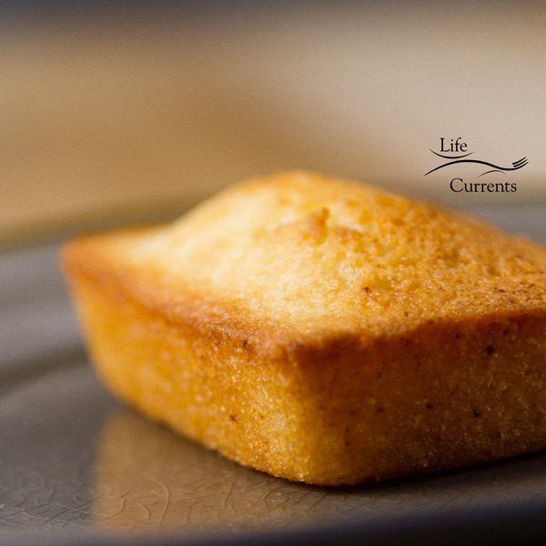 square image of the financier cake, a simple almond cake on a gray plate 