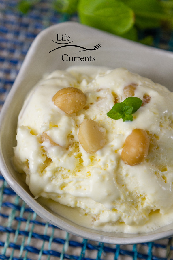 Pineapple Macadamia Nut Ice Cream in a white bowl garnished with macadamia nuts and a sprig of mint on blue fabric 